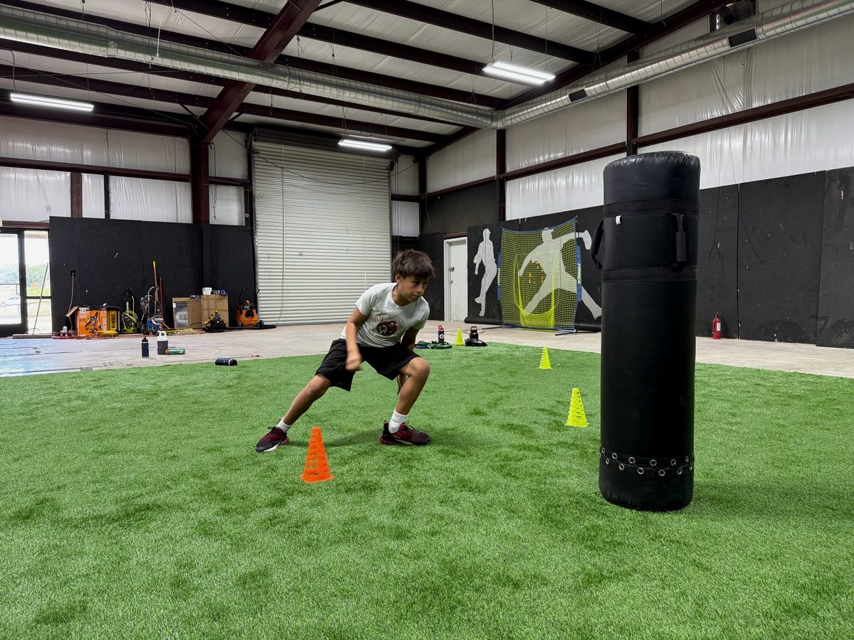 A student running an agility drill through cones on the turf