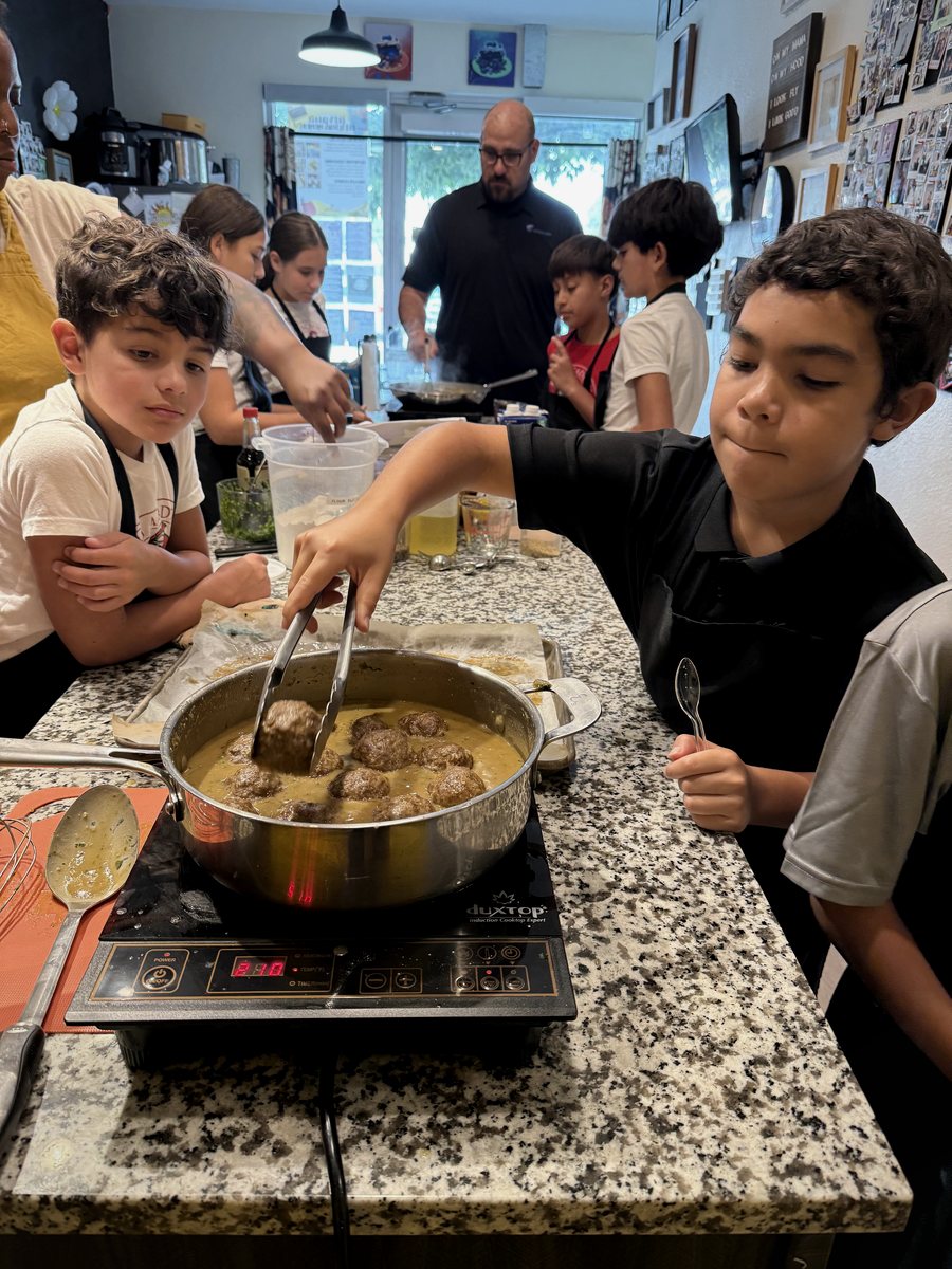 An LFG Academy student turning meatballs in a pan during cooking class
