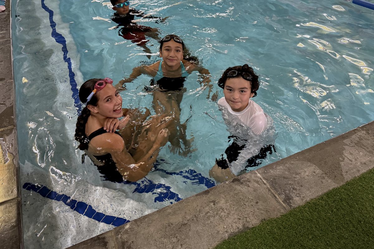 Four LFG Academy students at the wall of the pool during swim class
